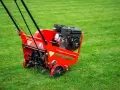 Czerwony aerator WEIBANG na zielonej trawie, gotowy do pracy. To urządzenie zapewnia doskonałą aerację trawnika, poprawiając jego wygląd i zdrowie.